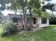 Inviting home featuring a covered porch, manicured lawn, and mature trees at 5736 Colonial Dr, New Port Richey, FL 34653