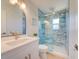 Bright bathroom showcasing a modern vanity with a unique mirror and a glass-enclosed shower with stylish blue tiling at 6432 Boatyard Dr, Hudson, FL 34667