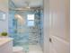 Beautiful bathroom featuring a glass shower enclosure with blue tiling and modern fixtures, complemented by a sleek white toilet at 6432 Boatyard Dr, Hudson, FL 34667