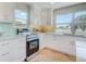 Bright kitchen showcasing white cabinets, tiled backsplash, stainless steel appliances, and wood floors at 6432 Boatyard Dr, Hudson, FL 34667