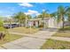 Charming home with palm trees, featuring a side view of the property and a paved driveway in a residential neighborhood at 7365 Pinehurst Dr, Spring Hill, FL 34606