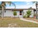 Inviting single-story home with mature landscaping, a red front door, and a well-maintained lawn on a sunny day at 7365 Pinehurst Dr, Spring Hill, FL 34606