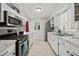 Galley kitchen featuring white cabinets, modern appliances, and neutral countertops at 7365 Pinehurst Dr, Spring Hill, FL 34606