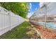 The lush backyard features a white fence, green grass, and a screened pool area for ultimate privacy at 7466 Jonquil Pl, Weeki Wachee, FL 34607