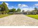 Charming home featuring a long, patterned brick driveway, well-manicured lawn, and beautiful mature trees at 7466 Jonquil Pl, Weeki Wachee, FL 34607