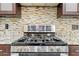 Close up view of stainless gas range with custom backsplash and granite countertops at 7466 Jonquil Pl, Weeki Wachee, FL 34607