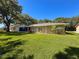 Enjoy this home's expansive backyard with lush green grass and mature trees on a sunny day at 7700 Fairlawn Dr, Hudson, FL 34667