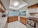 Well-lit kitchen featuring wood cabinets, tile countertops, and stainless steel appliances at 7700 Fairlawn Dr, Hudson, FL 34667
