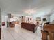Open-concept living area features tile flooring, a comfortable sofa, and seamless flow into the dining and kitchen at 7700 Fairlawn Dr, Hudson, FL 34667