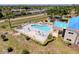 Aerial view of a fenced community pool with ample lounge chairs and umbrellas for relaxation at 8523 Regal Ln, Hudson, FL 34667