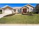 Inviting single-story home featuring a well-manicured lawn, verdant landscaping, and a charming red double-door entrance at 8523 Regal Ln, Hudson, FL 34667