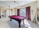 Game room with a red pool table, plush carpet, large window, and natural light filling the room at 8523 Regal Ln, Hudson, FL 34667