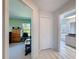 Hallway view into an office/bedroom and a bathroom; closet door visible; neutral walls and tile flooring throughout at 8523 Regal Ln, Hudson, FL 34667