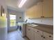Bright laundry room with modern washer and dryer, ample storage, and utility sink at 8523 Regal Ln, Hudson, FL 34667