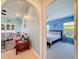 View from living room into a blue bedroom with windows, neutral carpet, and a queen bed with patterned bedding at 8523 Regal Ln, Hudson, FL 34667