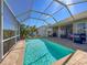 Backyard oasis showcasing a sparkling screened-in pool, brick pavers, outdoor seating, and barbecue grill at 8523 Regal Ln, Hudson, FL 34667