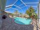 Sparkling private pool enclosed in a screened lanai, surrounded by lush landscaping at 8523 Regal Ln, Hudson, FL 34667
