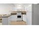 Compact kitchen featuring white cabinetry, modern appliances, and tiled backsplash at 9811 Hidden Ln # 2, Port Richey, FL 34668