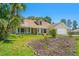 Inviting one-story home with a front porch and lush landscaping, including mature palm trees and flower beds at 10540 Noddy Tern Rd, Weeki Wachee, FL 34613