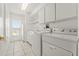Bright laundry room with white cabinets, appliances, and tiled floors at 10540 Noddy Tern Rd, Weeki Wachee, FL 34613