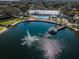 Stunning aerial view of a community lake with fountain, pier with gazebo, and community pool at 10641 Timber Ln, Port Richey, FL 34668