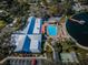 Aerial view of community center with pool, shuffleboard courts, lake access, and parking at 10641 Timber Ln, Port Richey, FL 34668