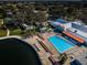 Aerial of community pool area with lounge chairs, tables, lakeside, and green space at 10641 Timber Ln, Port Richey, FL 34668