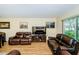 Cozy living room featuring wood-look floors, leather couches, and a large window at 10641 Timber Ln, Port Richey, FL 34668
