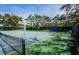 Well-maintained community tennis court with scoreboard, mature trees, and comfortable bench seating at 10641 Timber Ln, Port Richey, FL 34668