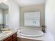 Bright bathroom featuring a soaking tub under a window and a vanity with a sink at 1082 Nodding Shade Dr, Brooksville, FL 34604