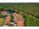 Aerial view of a vibrant community featuring cozy homes with backyard pools and a scenic pond in the distance at 1171 Dartford Dr, Tarpon Springs, FL 34688