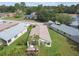 Aerial view displaying a white house with a brown roof and screen lanai, set amidst a green lawn with mature trees at 11732 Wheatfield Loop, Hudson, FL 34667