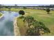 Aerial view of a golf course and lake, highlighting lush green landscaping and mature trees, perfect for recreation at 11732 Wheatfield Loop, Hudson, FL 34667