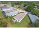 An aerial view displays a white home with a light-brown roof, lush landscaping, and a screened lanai at 11732 Wheatfield Loop, Hudson, FL 34667