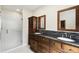 Bathroom with double sinks, granite counters, shower, and dark wood cabinets at 11732 Wheatfield Loop, Hudson, FL 34667