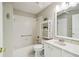 Bright bathroom with white fixtures, decorative shelving and tub with shower at 11732 Wheatfield Loop, Hudson, FL 34667
