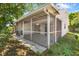 Exterior view of a screened porch and backyard with green foliage at 12204 Pepper Mill Dr, Hudson, FL 34667