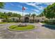 Exterior view of the Crescent Oaks clubhouse with a circular drive, mature palms, and American flag on display at 1260 Dartford Dr, Tarpon Springs, FL 34688