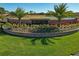 Landscaped brick entrance to Crescent Oaks featuring colorful flowers, mature palms and lush green grass at 1260 Dartford Dr, Tarpon Springs, FL 34688