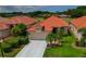 Beautiful single-story home with a well-manicured lawn, lush landscaping, and a red tile roof at 1260 Dartford Dr, Tarpon Springs, FL 34688