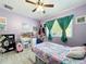 bedroom with purple walls, playful decor, a large window, and bed creating a fun and inviting space at 13111 Sheridan Dr, Hudson, FL 34667