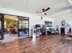 A well-lit room with wood flooring, a ceiling fan, and sliding glass doors opening to a sunroom at 13111 Sheridan Dr, Hudson, FL 34667