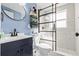 Modern bathroom featuring a glass shower, white tiled walls, and blue vanity with an above-counter sink at 13632 Britton Dr, Hudson, FL 34667