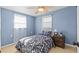 Cozy bedroom featuring blue walls, a ceiling fan, and a comfortable bed with matching floral-patterned bedding at 13632 Britton Dr, Hudson, FL 34667