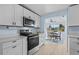 Bright kitchen showcasing white cabinets, stainless steel appliances, and wood-look tile floors at 13632 Britton Dr, Hudson, FL 34667