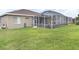 A green, grassy backyard with a screened-in lanai and a glimpse of the pool at 13942 Talmage Loop, Hudson, FL 34667