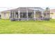 A view of a backyard with a screened-in lanai, pool, and grassy lawn at 13942 Talmage Loop, Hudson, FL 34667