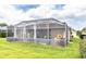A view of a backyard with a screened-in lanai, pool, and lawn at 13942 Talmage Loop, Hudson, FL 34667