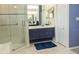 Bathroom with glass shower, vanity with blue cabinets, tile flooring and good lighting at 13942 Talmage Loop, Hudson, FL 34667