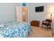 Comfortable bedroom with blue walls, a mounted TV, and connecting bathroom at 13942 Talmage Loop, Hudson, FL 34667